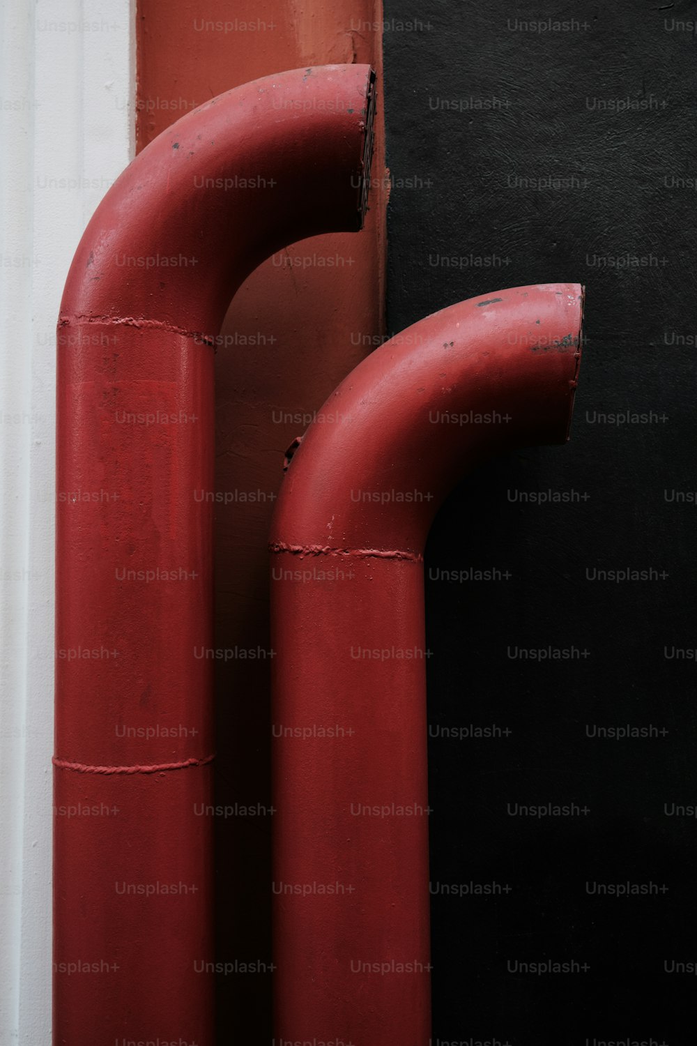 Ein Paar rote Rohre, die aus der Seite eines Gebäudes ragen