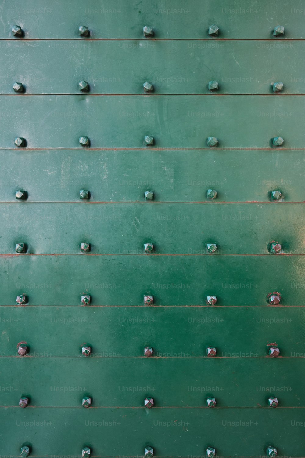 a close up of a green wall with rivets