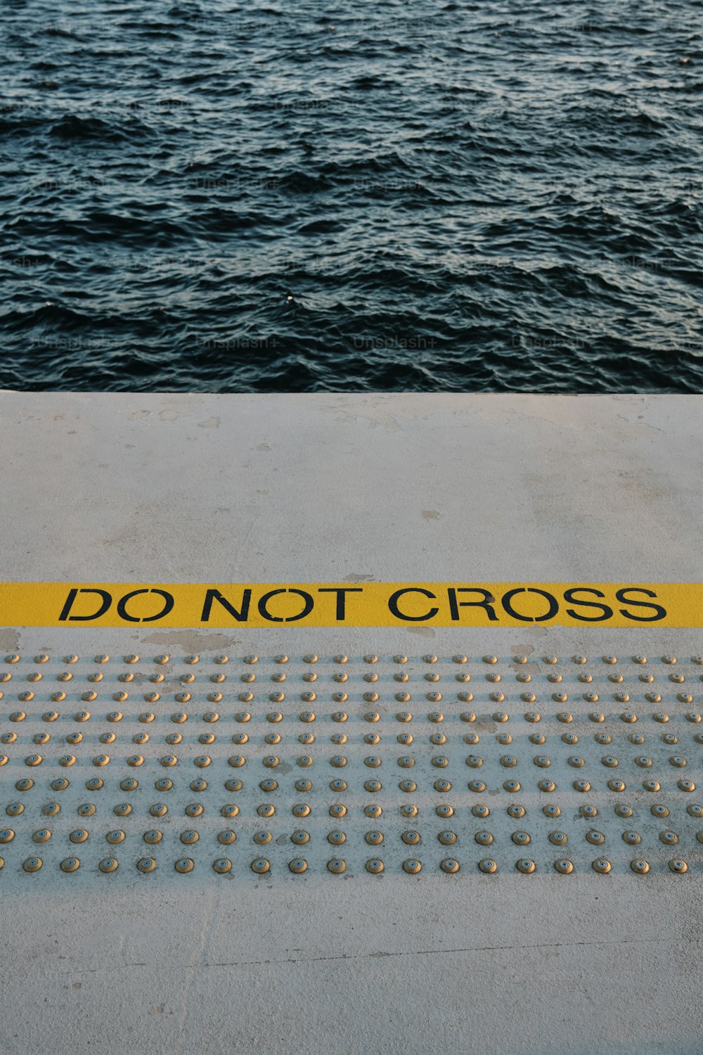 a yellow do not cross sign sitting on the side of a boat