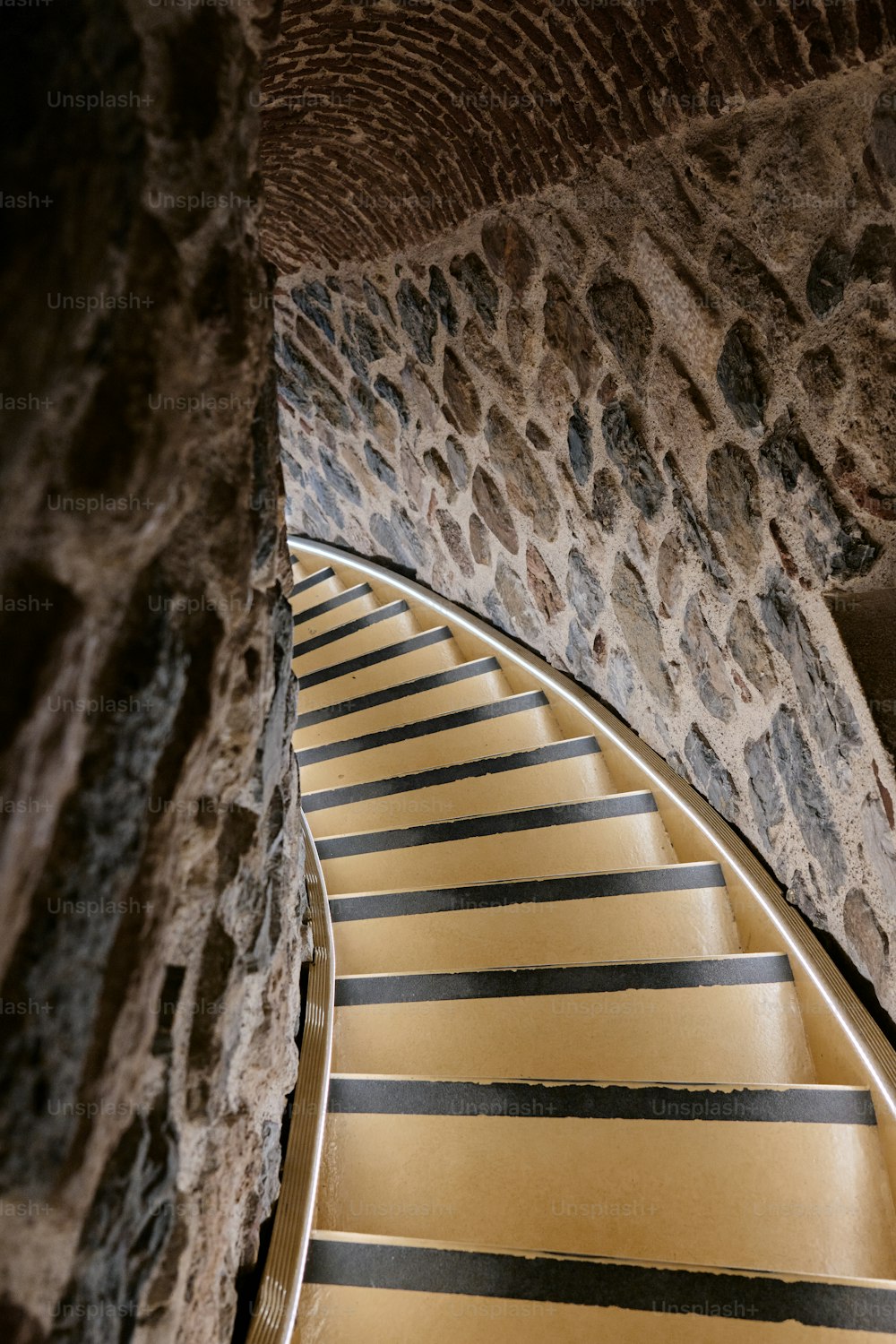 una escalera de rayas amarillas y negras junto a una pared de piedra