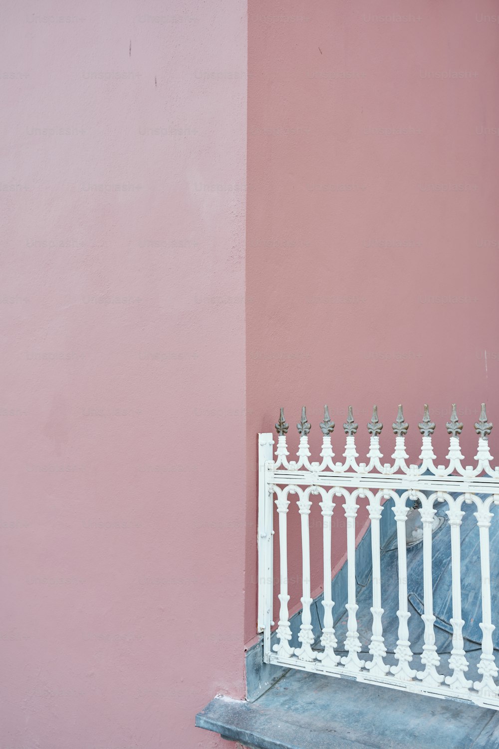 uma cerca de ferro branca contra uma parede rosa