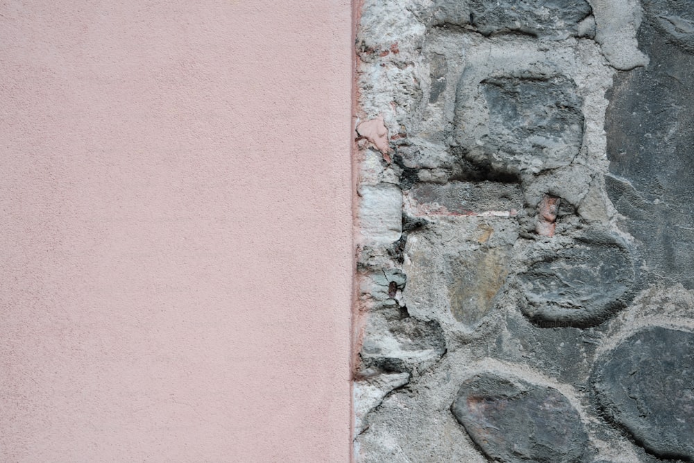 a stone wall with a pink wall behind it