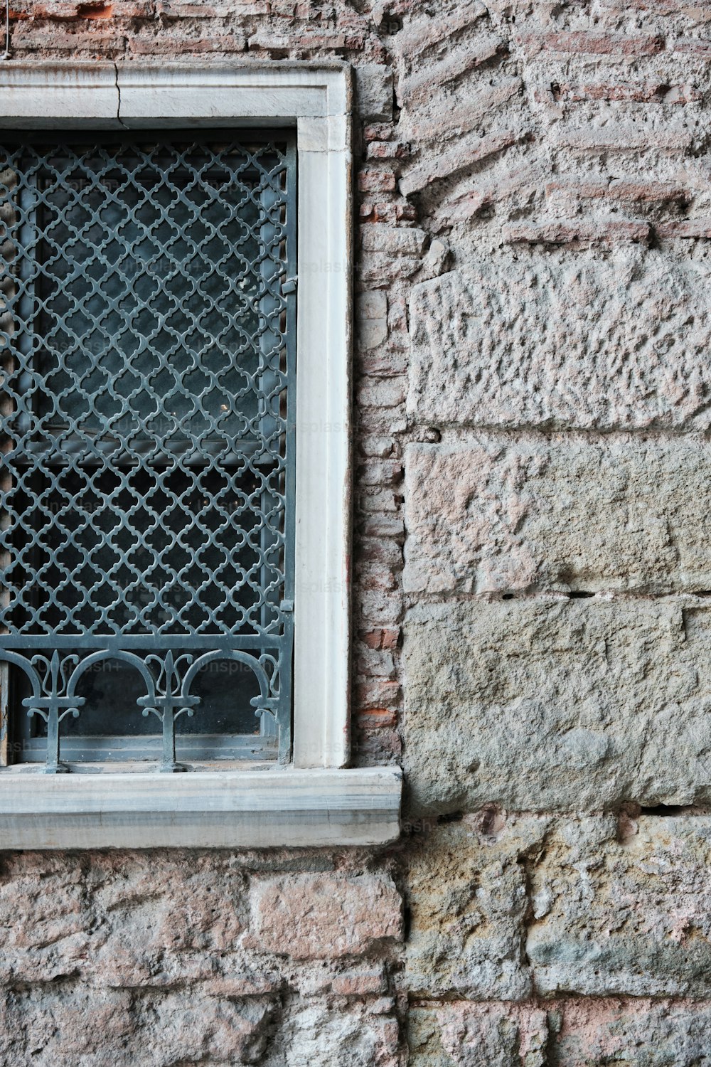 a window on a brick wall with a wrought iron grill