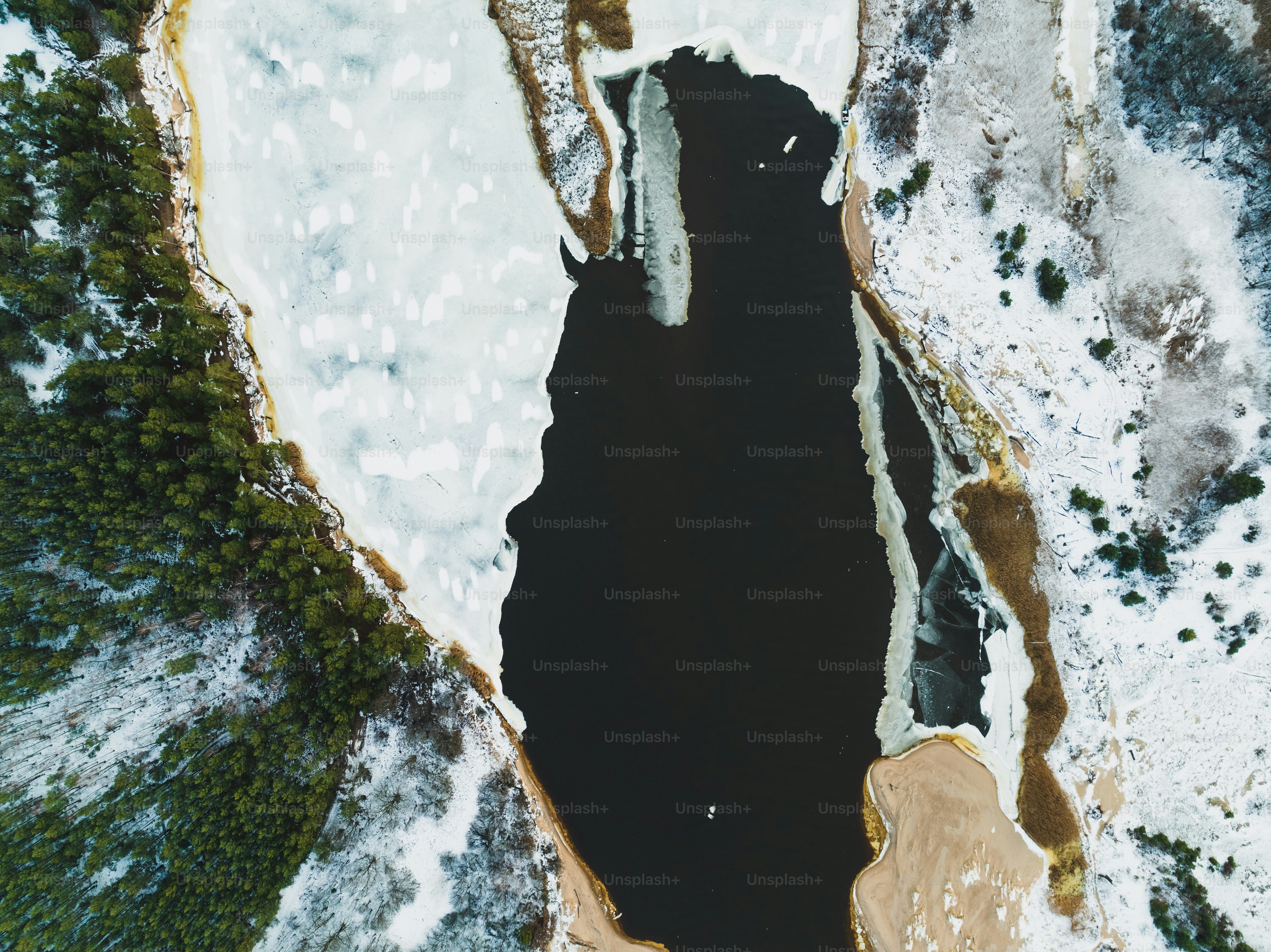 an aerial view of a lake surrounded by snow