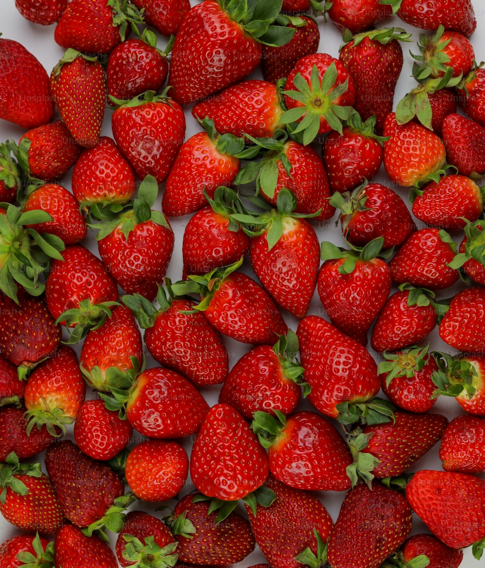a large group of strawberries on a white surface