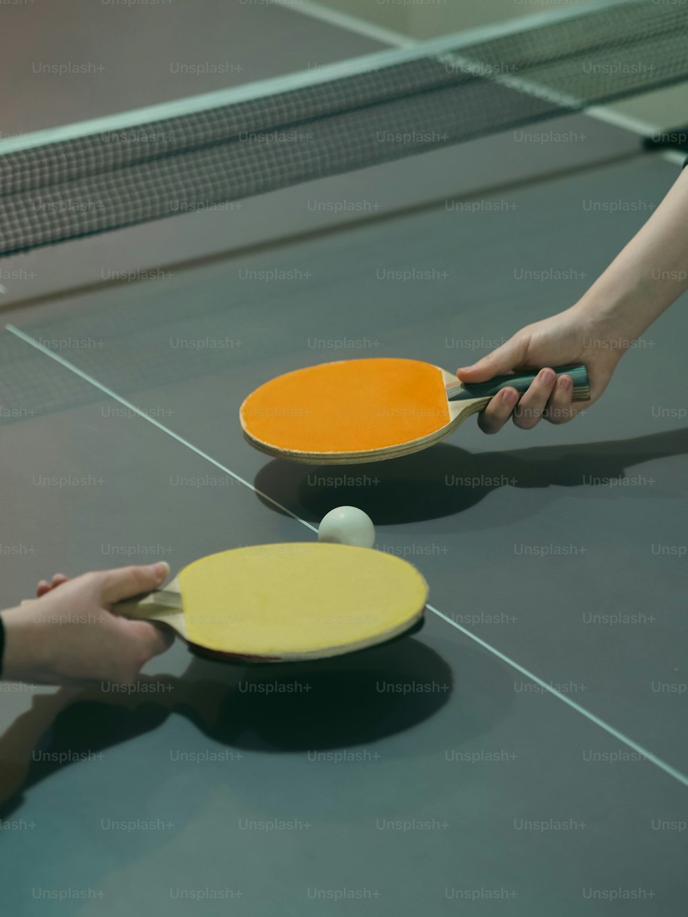 two people are playing ping pong on a ping pong table