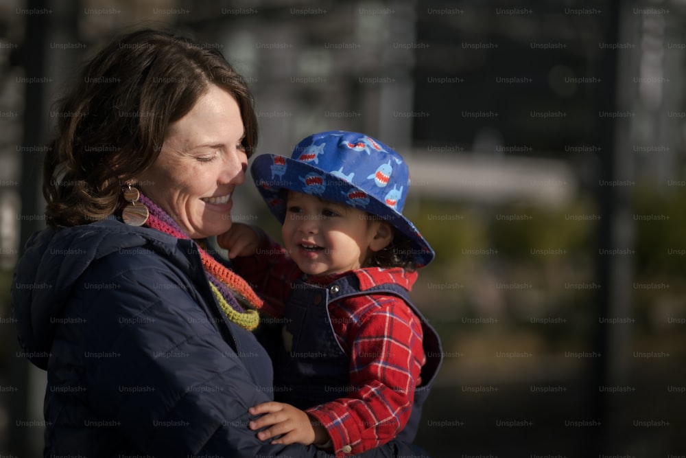 une femme tenant un enfant portant un chapeau bleu