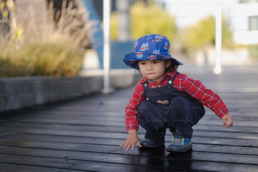 a small child wearing a blue hat and overalls