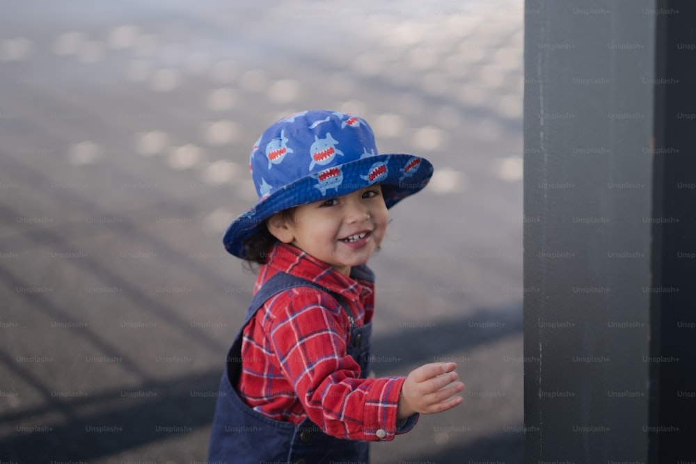 Un jeune garçon portant un chapeau et un gilet bleus