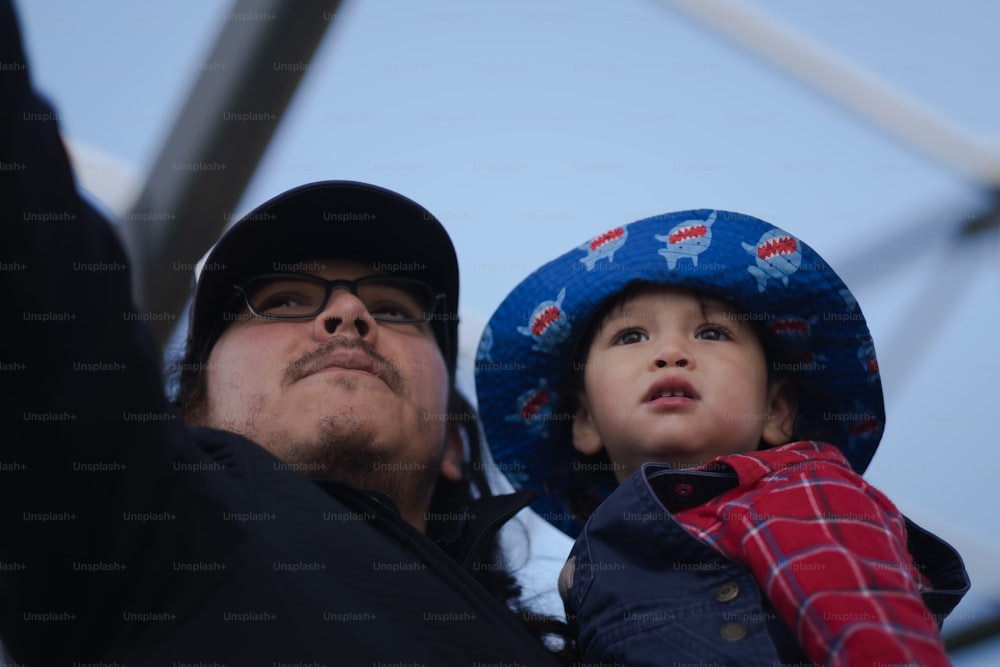 a man holding a child wearing a cowboy hat