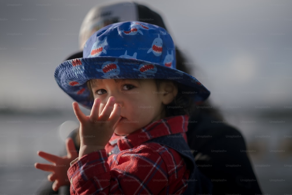a small child wearing a blue hat and making a hand gesture