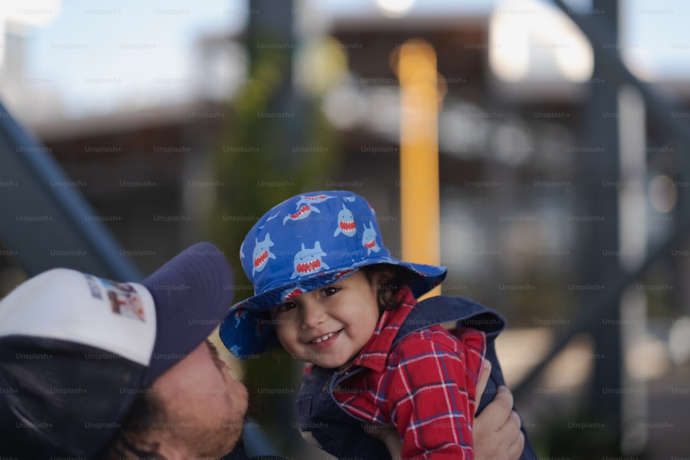 Un uomo che tiene in braccio un bambino piccolo che indossa un cappello