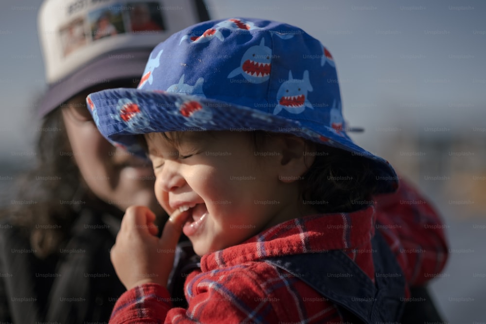 uma criança pequena usando um chapéu azul e sorrindo