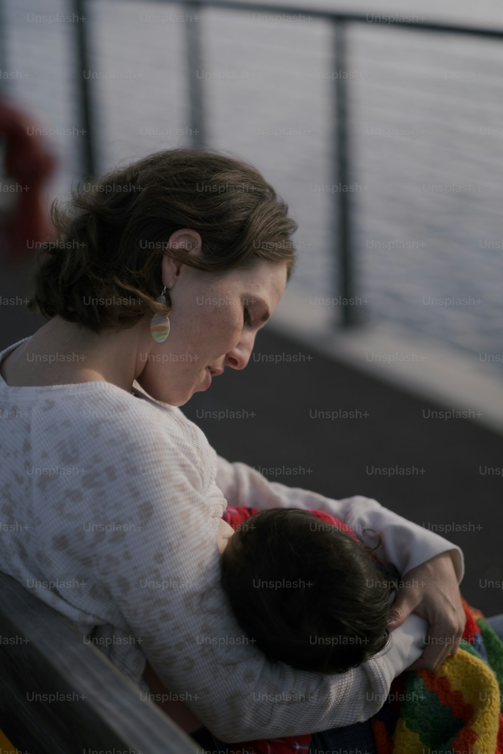 a woman holding a baby while sitting on a bench