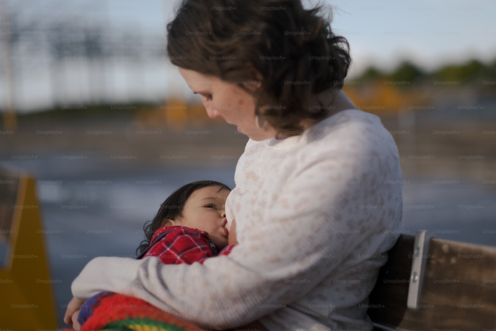 a woman sitting on a bench holding a child