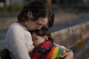 a woman holding a child on a bench