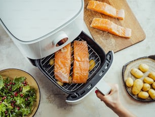 une personne utilise une friteuse à air pour cuire du saumon