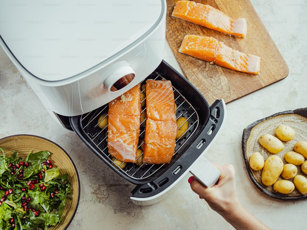 a person is using an air fryer to cook salmon