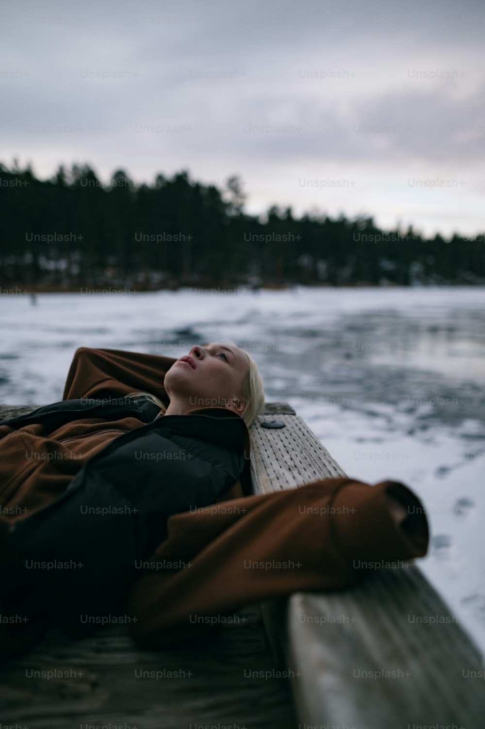 a woman laying down on a dock in the snow