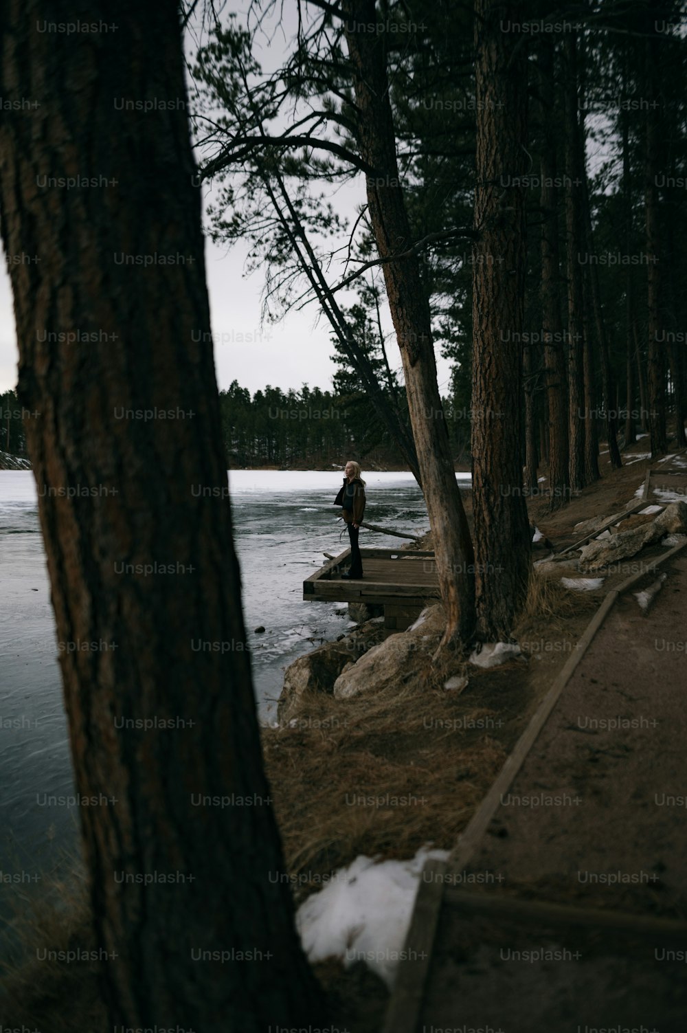 uma pessoa de pé em um caminho ao lado de um corpo de água