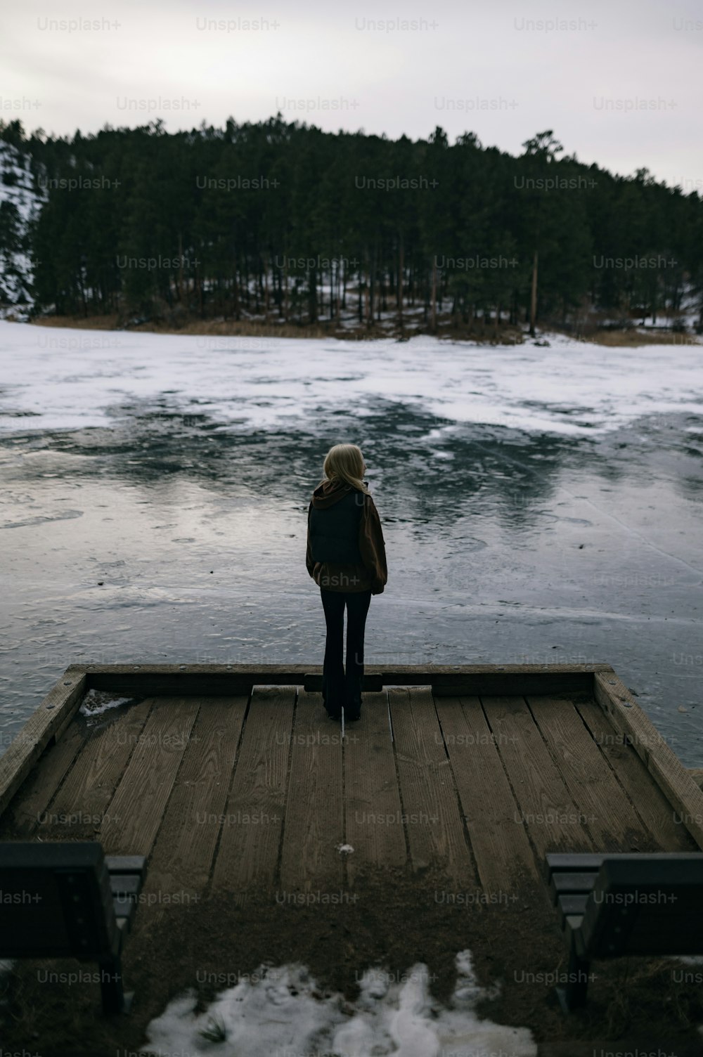 una persona in piedi su un molo che guarda l'acqua