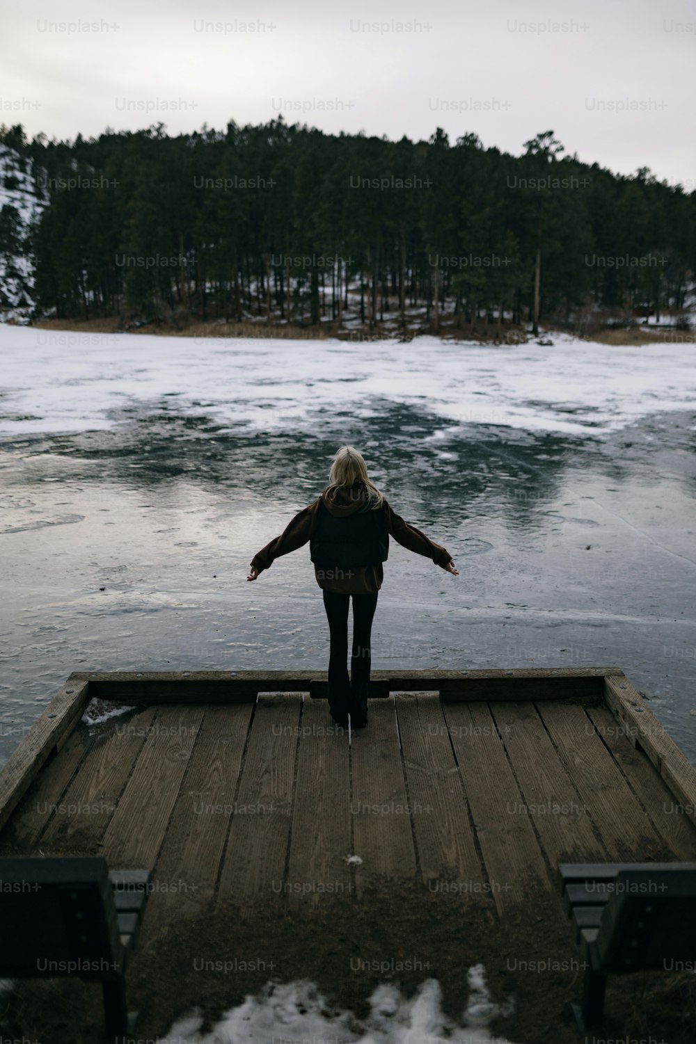 a woman standing on a dock in front of a body of water