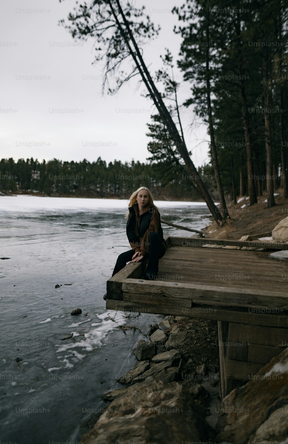 Une femme assise sur un quai près d’un plan d’eau