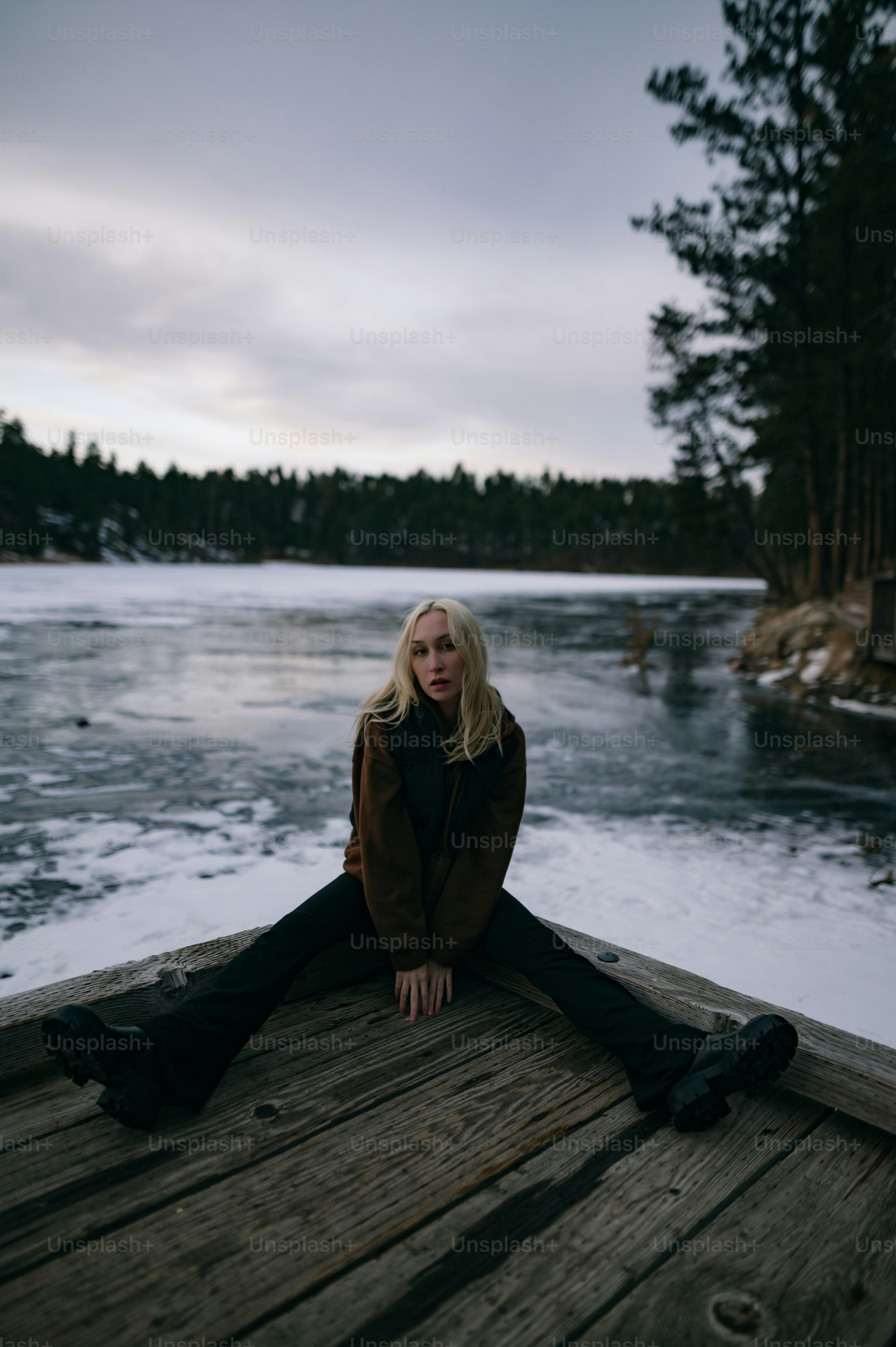 A woman is sitting on a dock by the water photo – Winter Image on Unsplash