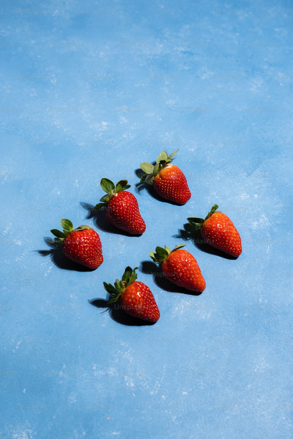 Eine Gruppe von fünf Erdbeeren auf blauer Oberfläche