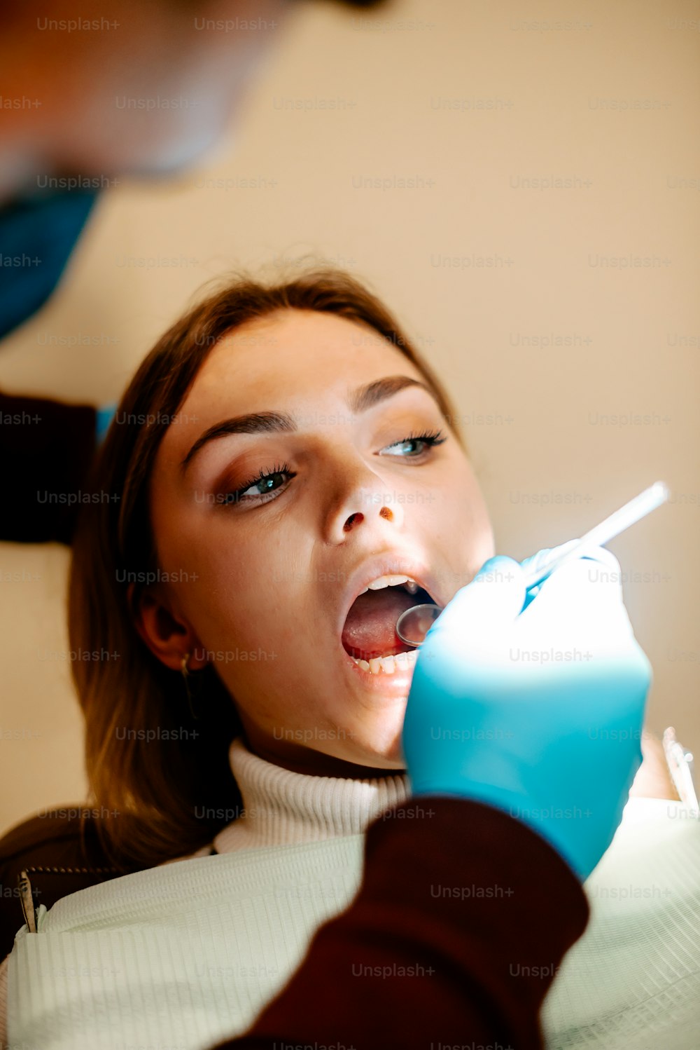 a woman getting her teeth brushed by a dentist
