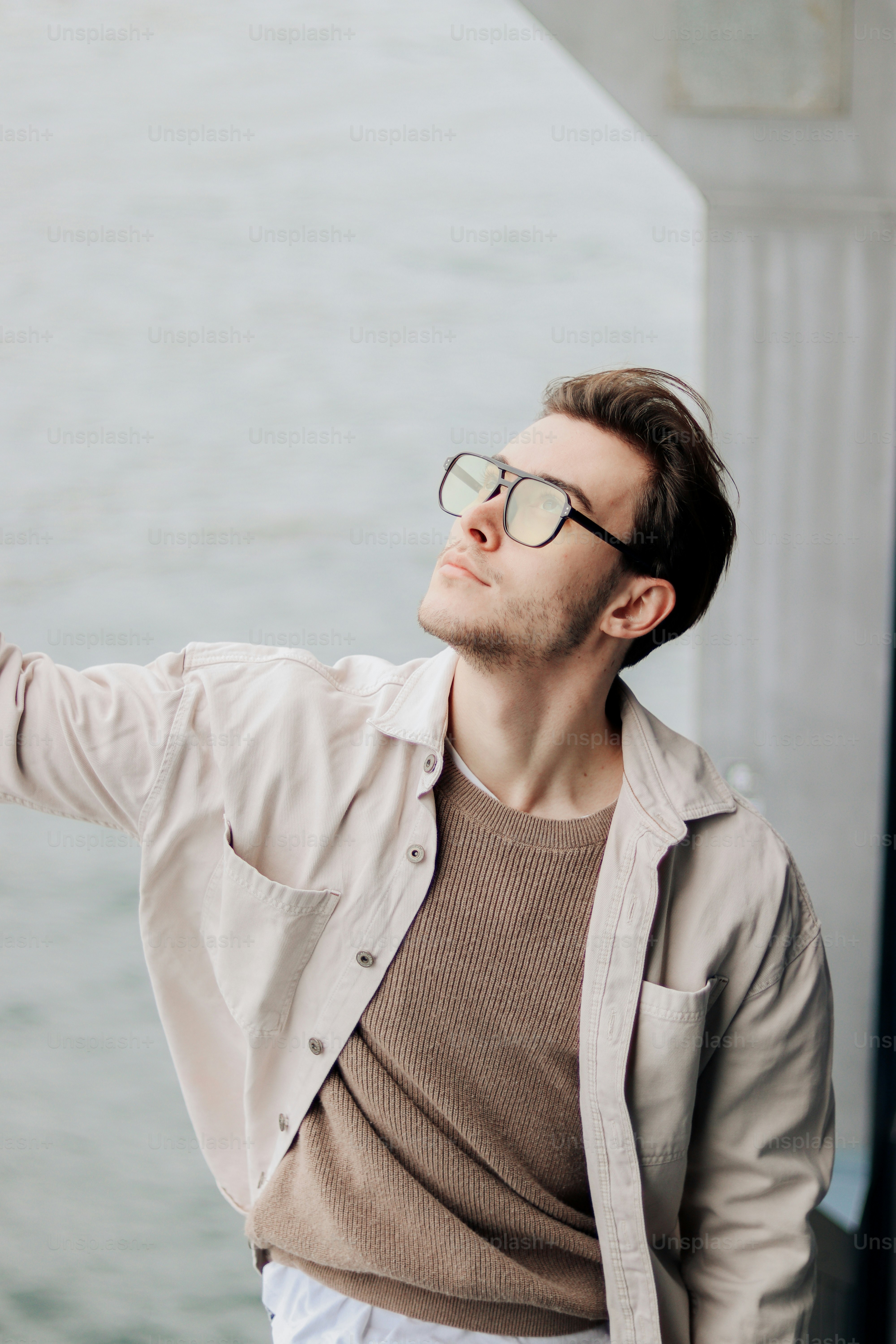 Un uomo che porta gli occhiali appoggiato a un muro