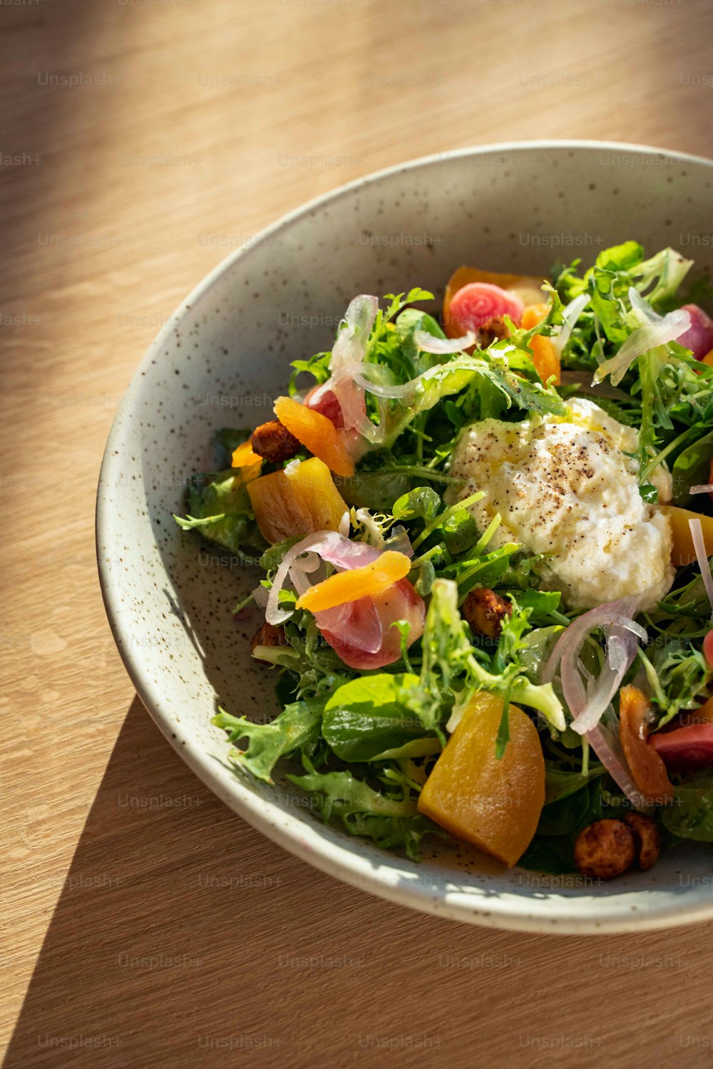 a white bowl filled with a salad on top of a wooden table