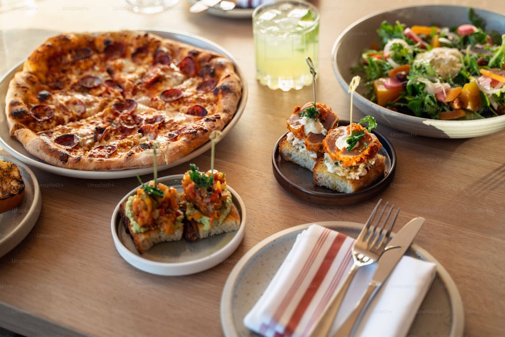 uma mesa coberta com pratos de comida e uma pizza