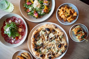 a table topped with plates of food and bowls of salad