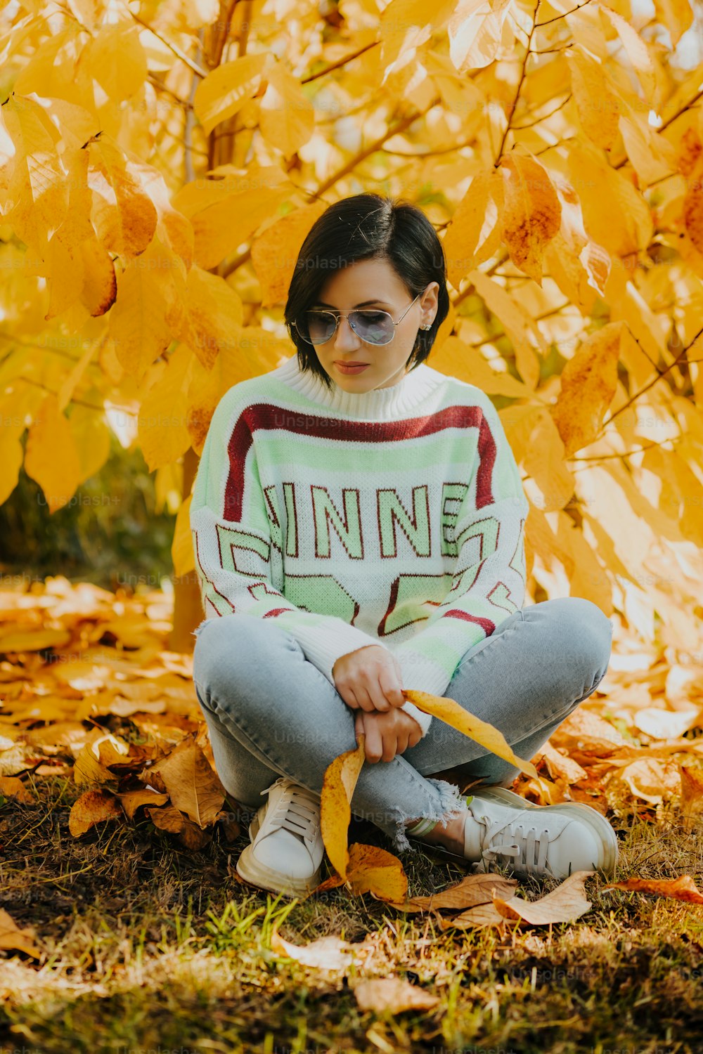 a woman sitting on the ground in front of a tree