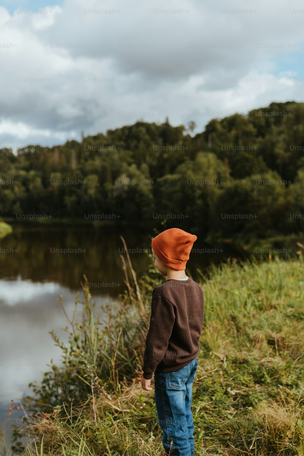 a young boy standing next to a body of water