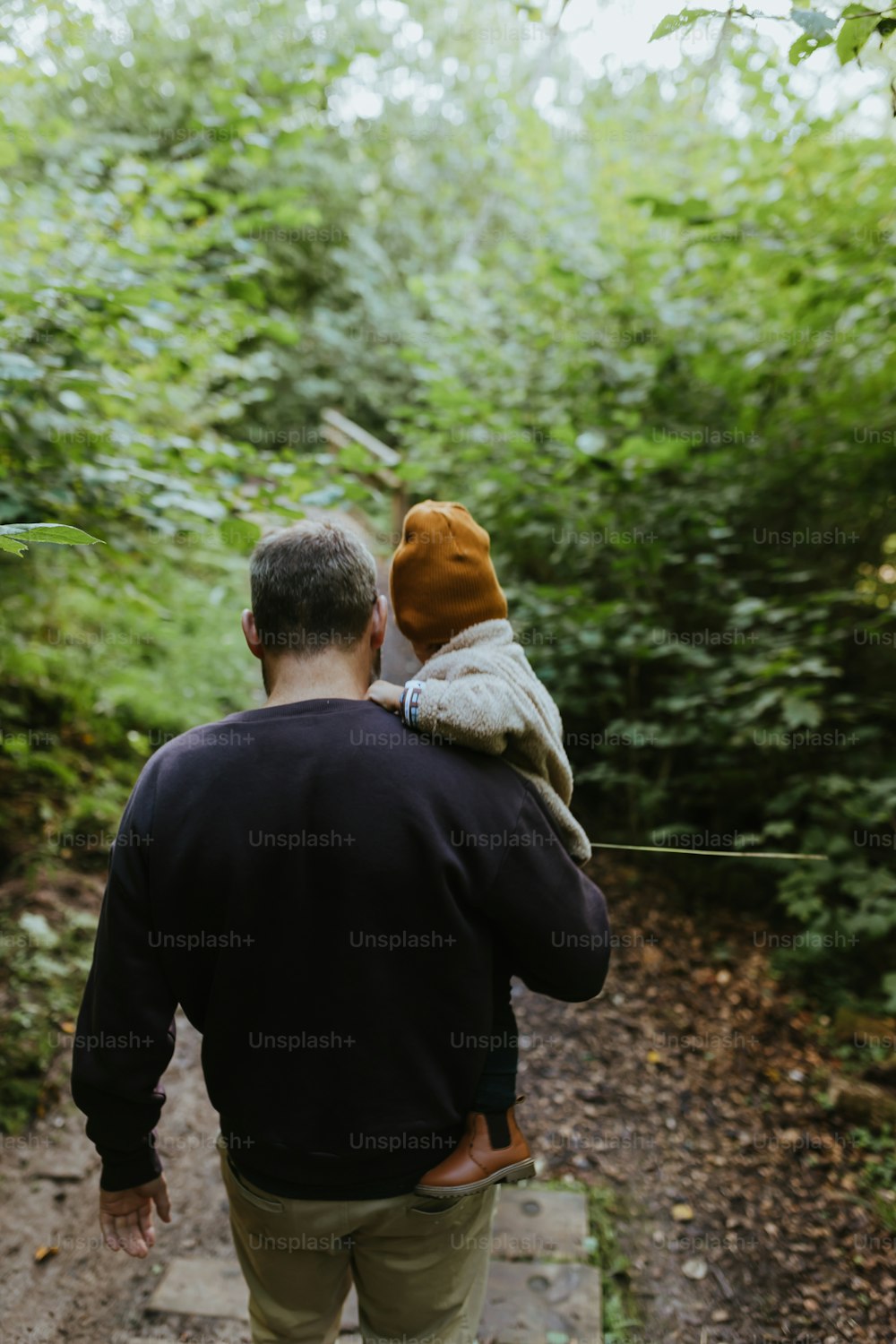 Un hombre caminando por un sendero con un niño en la espalda
