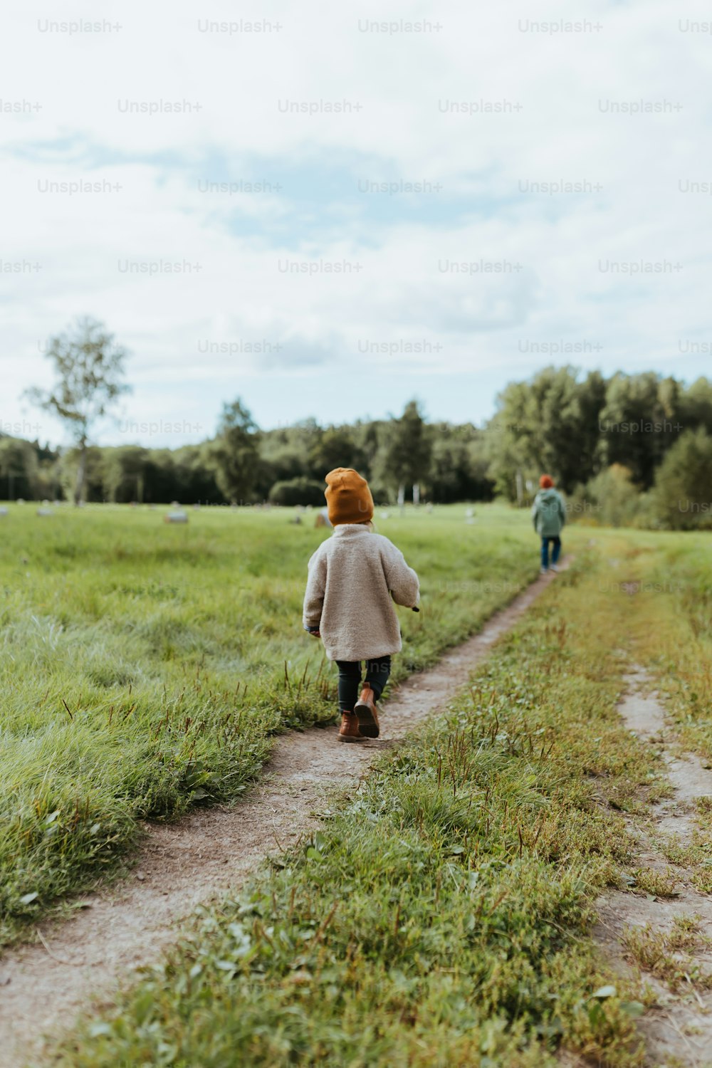 a little girl walking down a dirt road