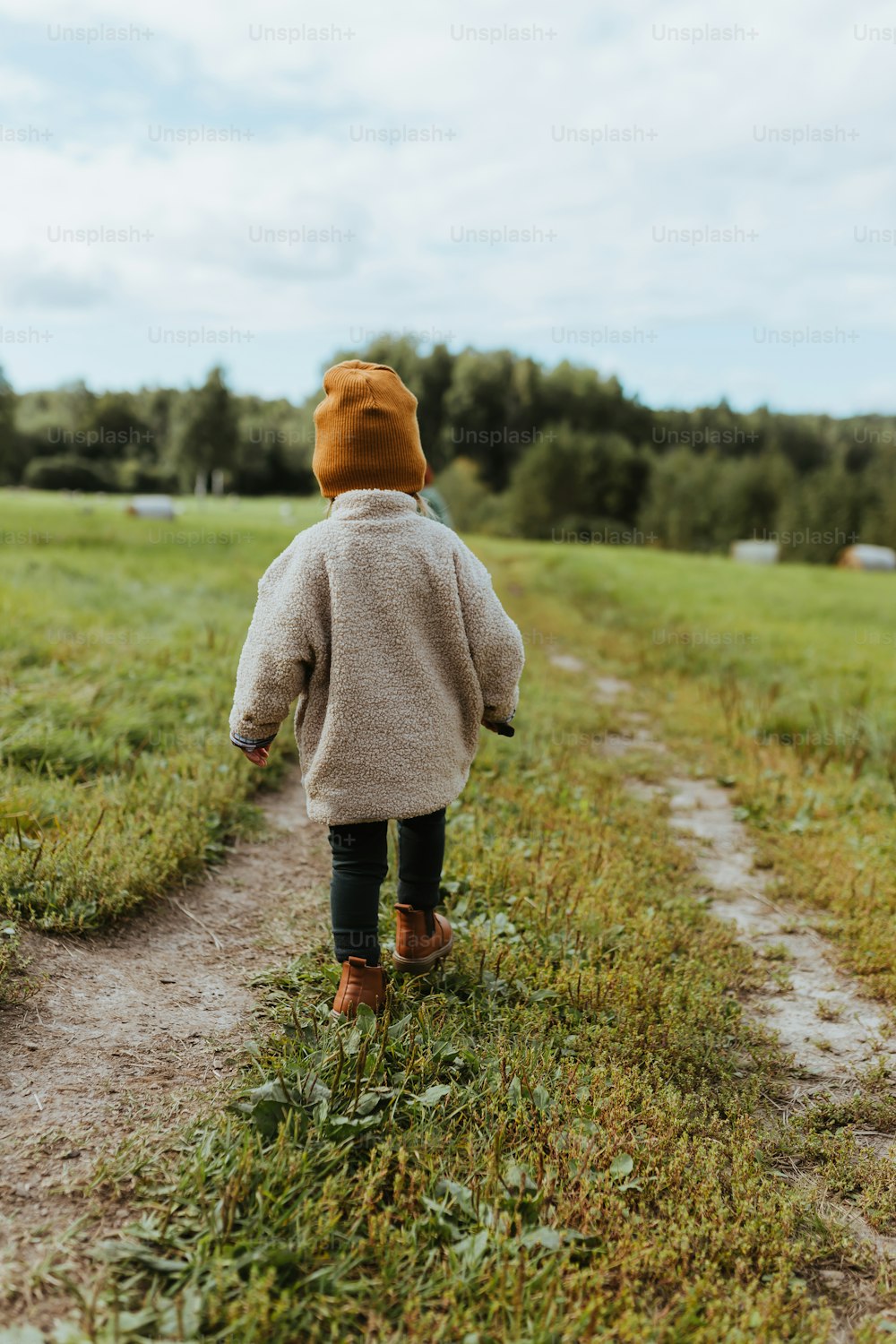 a young child walking down a dirt path
