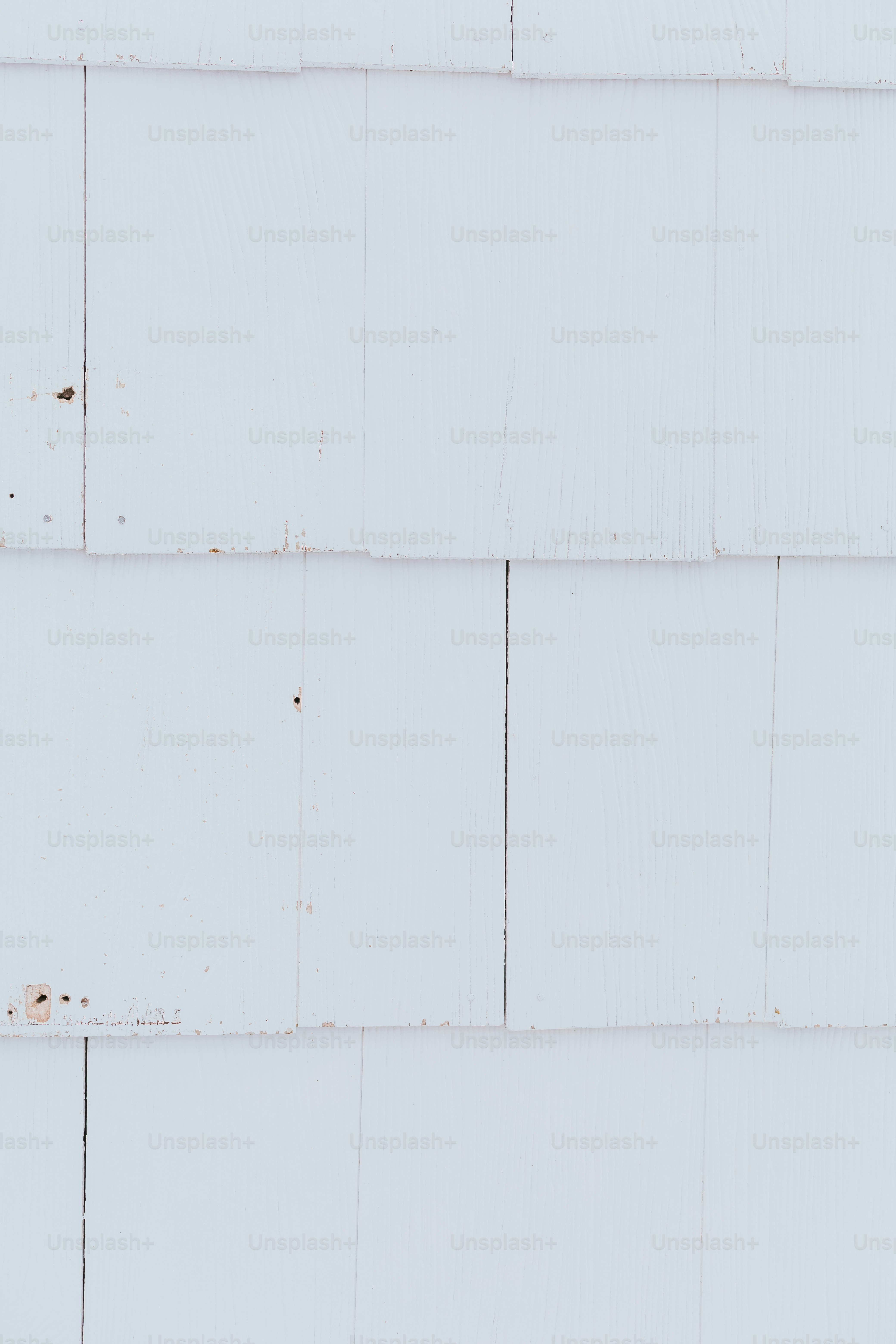 a red and white bird is perched on a white brick wall
