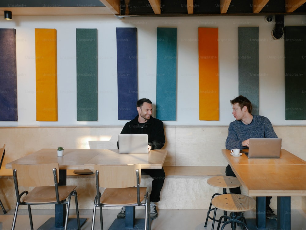 a couple of men sitting at a table with laptops