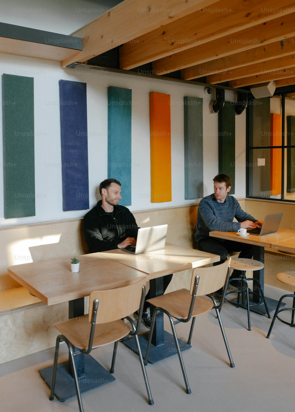 Un couple d’hommes assis à une table avec des ordinateurs portables