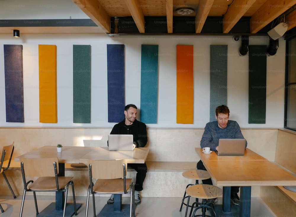 a couple of men sitting at a table with laptops