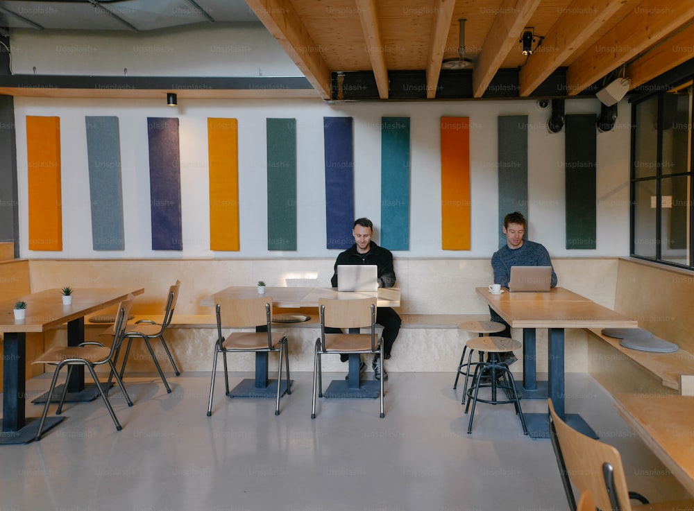 a couple of people sitting at a table with laptops