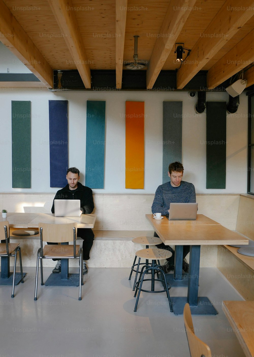 a couple of men sitting at a table with laptops