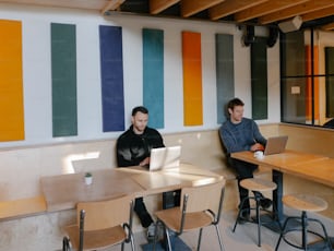 a couple of men sitting at a table with laptops