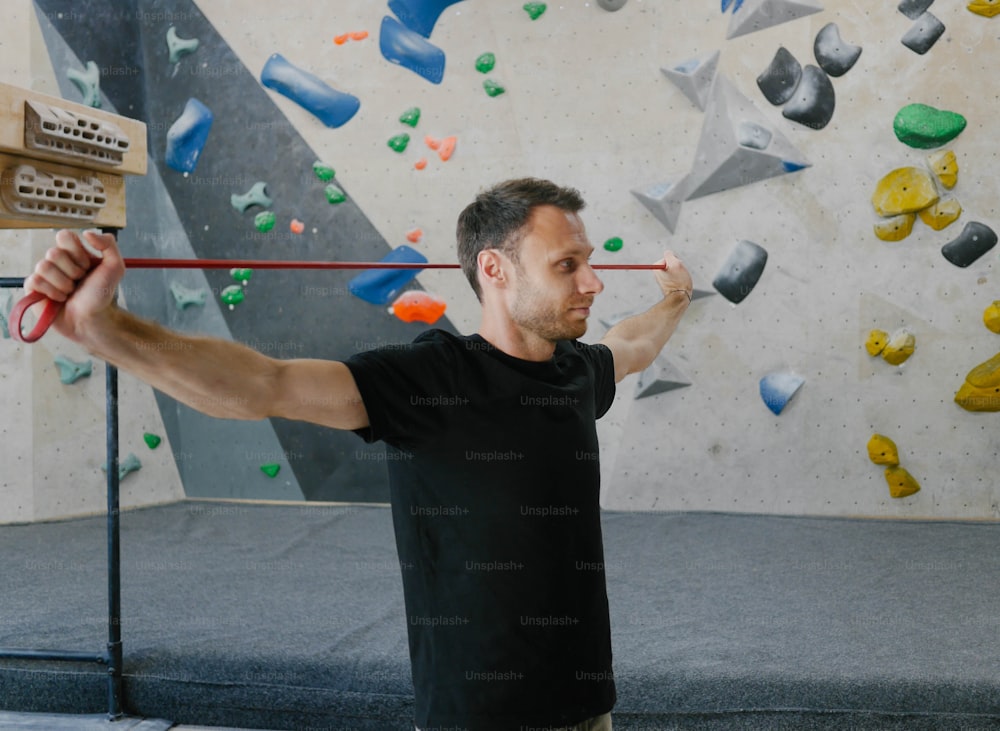 a man holding a bar in front of a climbing wall