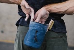 um homem segurando uma bolsa azul com um pincel nela