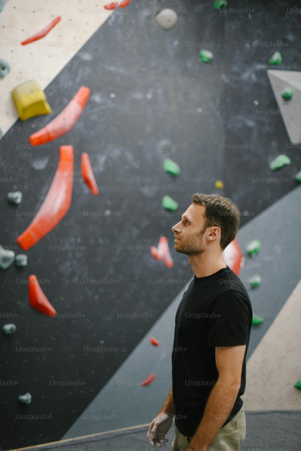 Un hombre parado frente a un muro de escalada