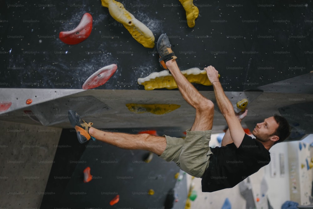 Un hombre en un muro de escalada con los pies en el aire